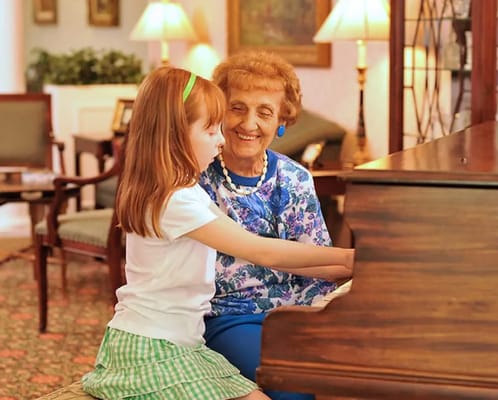 An elderly woman and a girl playing a piano together