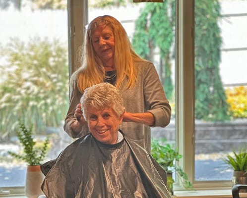A resident receiving a haircut in a cozy setting