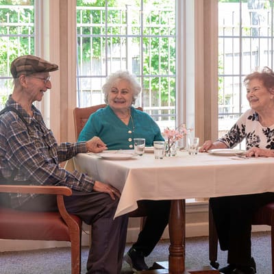 Three residents enjoying a meal together at a dining table