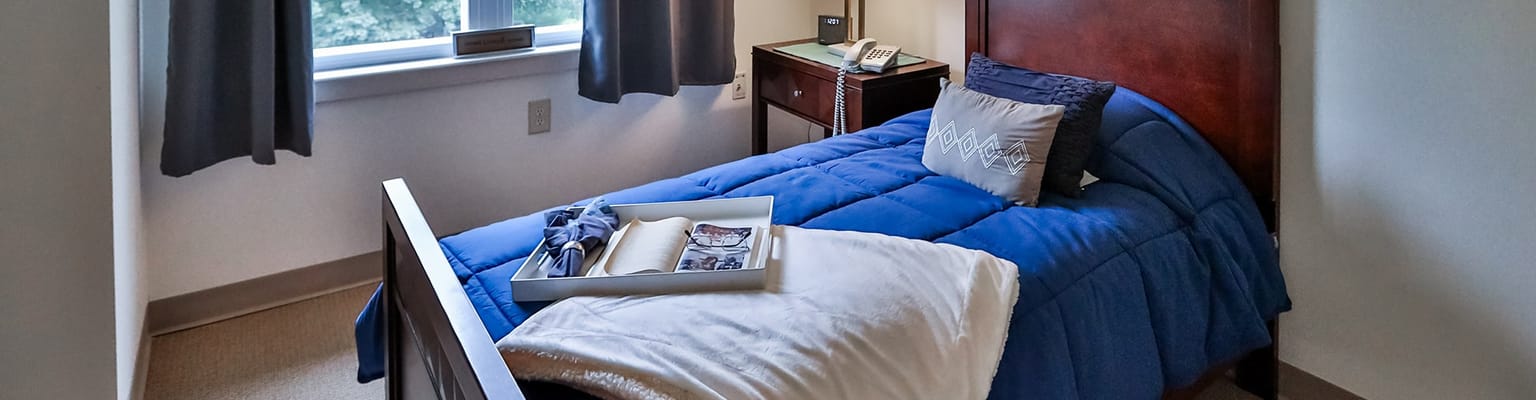Cozy resident room with blue bedding and window