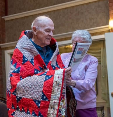 Residents participating in a celebration with a quilt