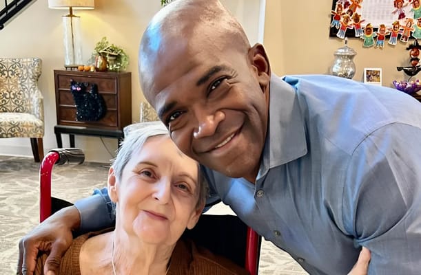 A resident smiling with a staff member in a common area