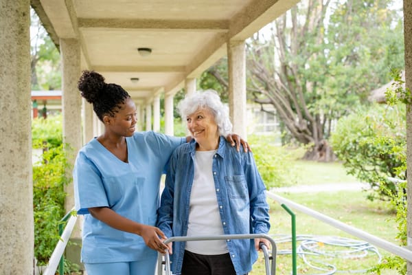 A caregiver assisting a senior resident outdoors