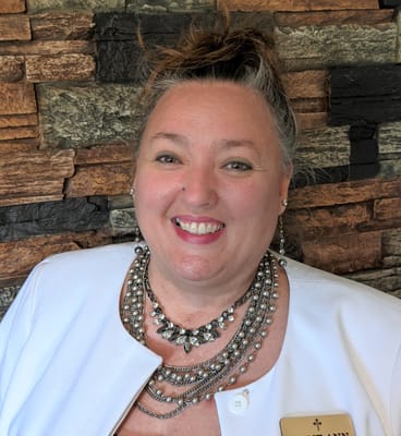 Staff member smiling in front of a stone wall