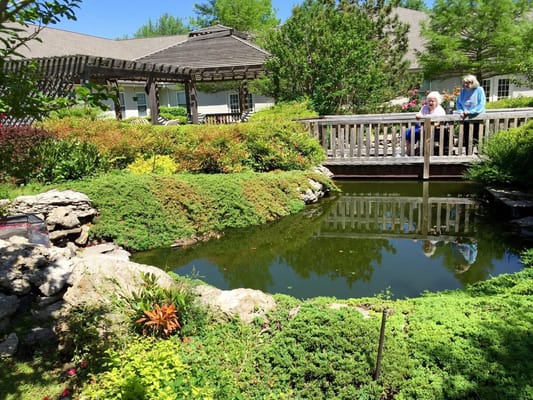 Residents enjoying a tranquil garden with a pond