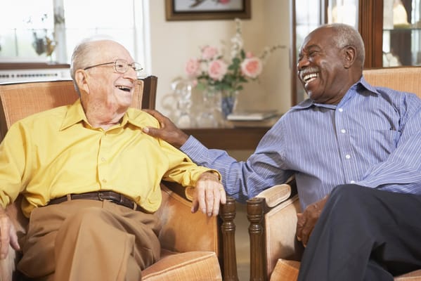 Two smiling seniors sharing a joyful moment in a common area