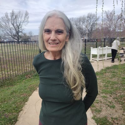 A smiling resident standing outdoors in a garden area