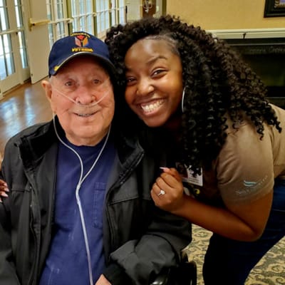 A resident and staff member smiling together in a common area