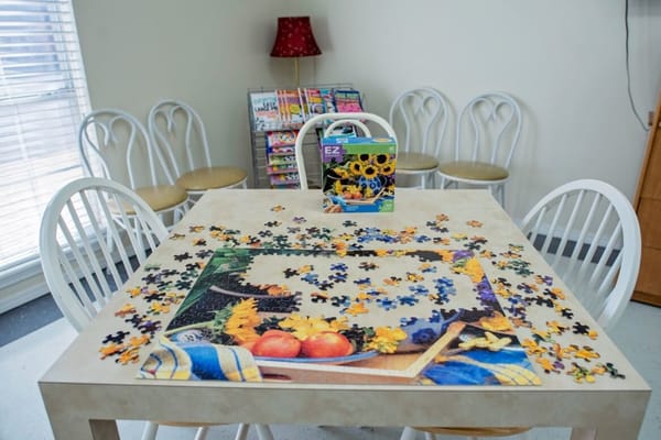 Residents working on a colorful jigsaw puzzle in a common area