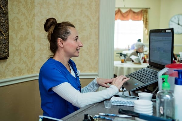 Staff member assisting with computer work in a common area
