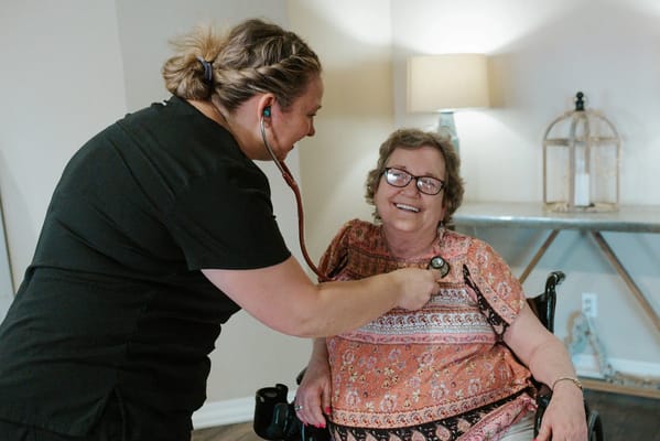 Staff member checking a resident's blood pressure in a cozy setting