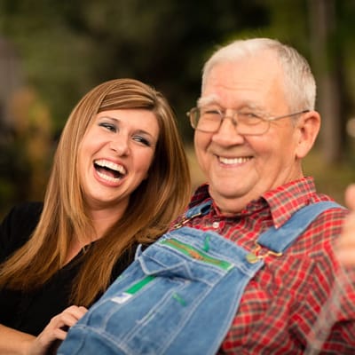 A caregiver and a resident smiling together outdoors