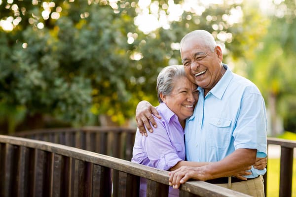 Couple smiling together on a wooden bridge in a garden