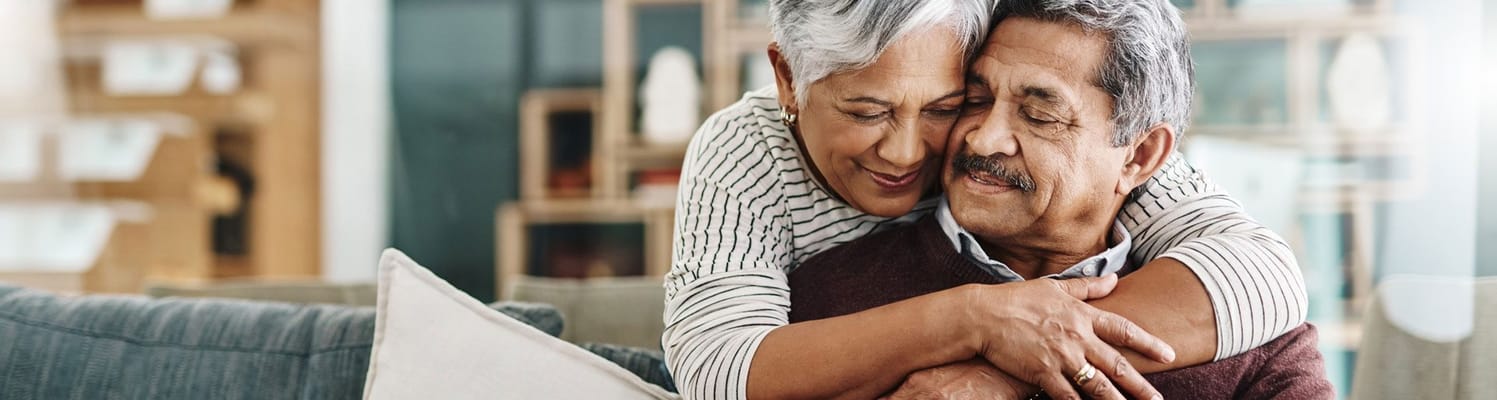 A senior couple embracing each other in a cozy indoor setting