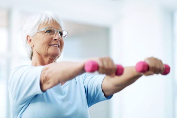 Senior woman exercising with dumbbells indoors