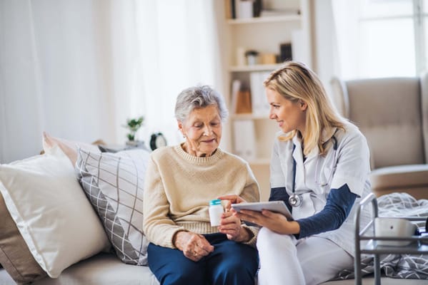 A caregiver discussing medication with an elderly woman