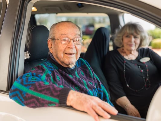Resident smiling in a vehicle with staff member