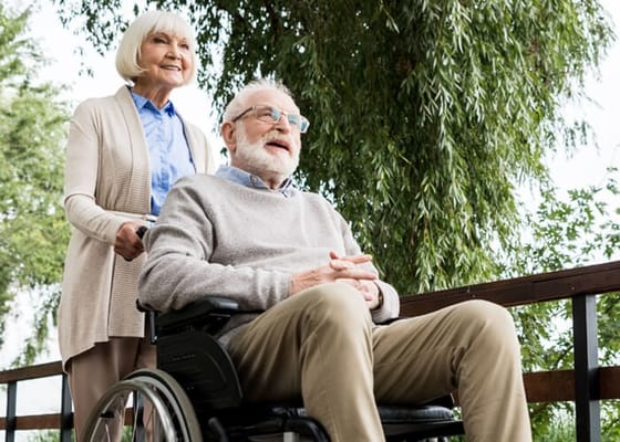 A resident in a wheelchair being assisted outdoors by a staff member