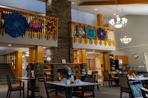 Dining area decorated with resident artwork and a resident reading