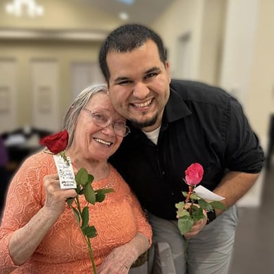 Resident and staff member posing with roses in a common area