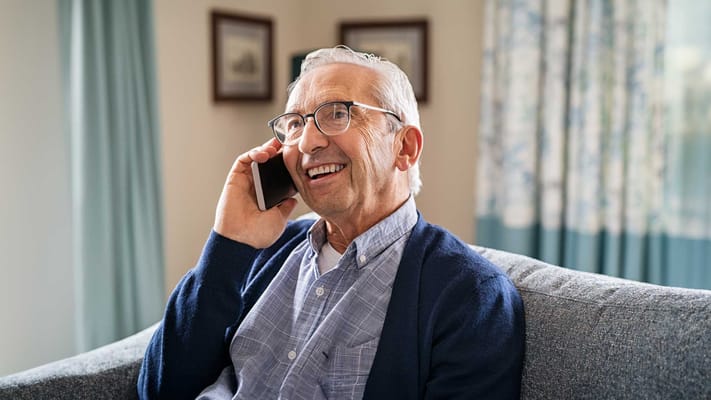 Senior resident happily talking on the phone in a cozy setting