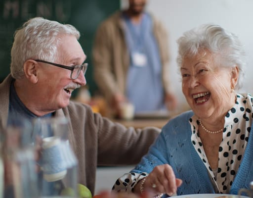 Two residents enjoying a meal and laughing together