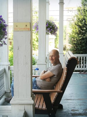A resident relaxing on a porch in a rocking chair