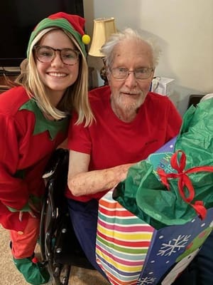 A smiling caregiver with an elderly resident during a gift exchange