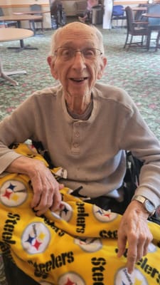 A resident smiling in a common area with a Steelers blanket