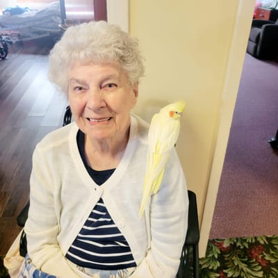 Resident smiling with a bird on their shoulder