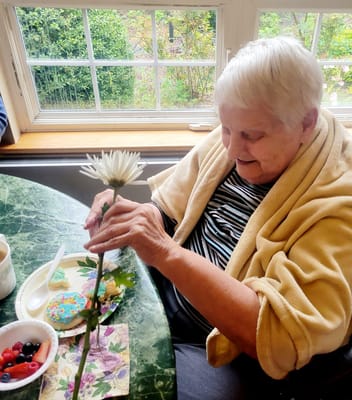 Resident crafts with flowers and cookies at a table