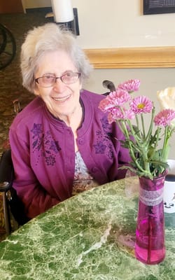 A smiling resident in a common area with flowers