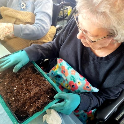A resident gardening indoors with soil and flowers