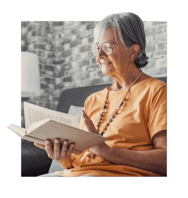 An elderly woman reading a book in a cozy interior