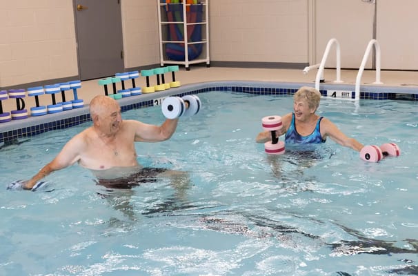 Residents exercising with water weights in a pool