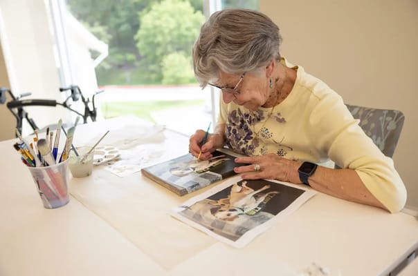 Resident painting at a table in an activity room