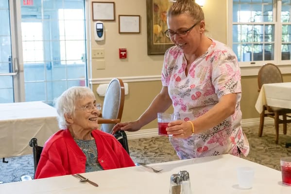 Staff serving a drink to a resident in a dining area