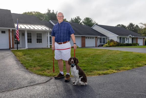 Resident with a dog in front of cottages