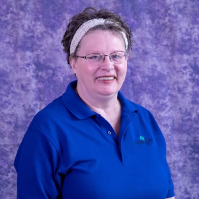 Staff member smiling in a blue shirt with logo