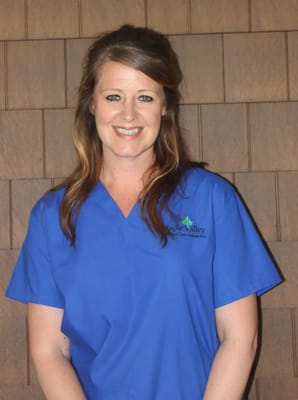 A staff member in blue scrubs smiling