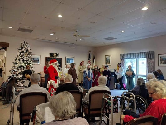 Residents enjoying a holiday performance with staff and Santa