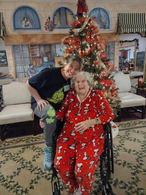 Resident and staff member celebrating by the Christmas tree