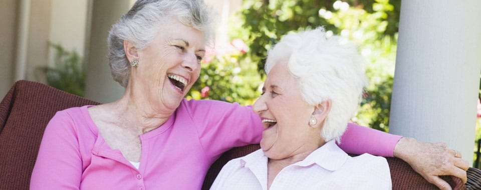 Two women laughing together in a cozy setting