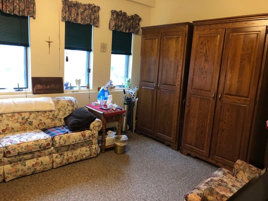 A cozy resident room with floral sofa and wooden furniture
