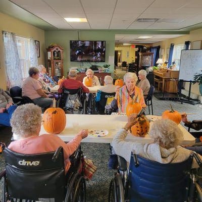 Residents participating in a pumpkin painting activity in a common area