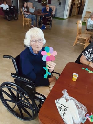 An elderly resident crafting a flower at a table