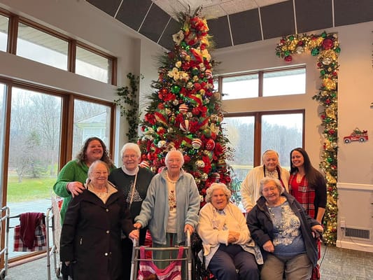 Residents and staff celebrating by a decorated tree
