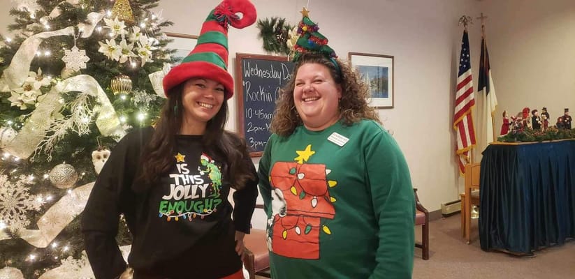 Two staff members in festive sweaters at a holiday event