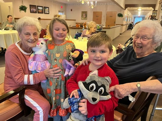 Residents and children engaging with stuffed animals in common area