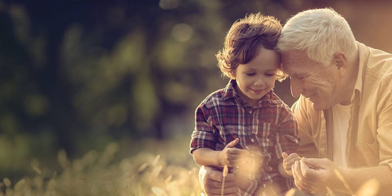 An elderly man enjoying time with a young child outdoors